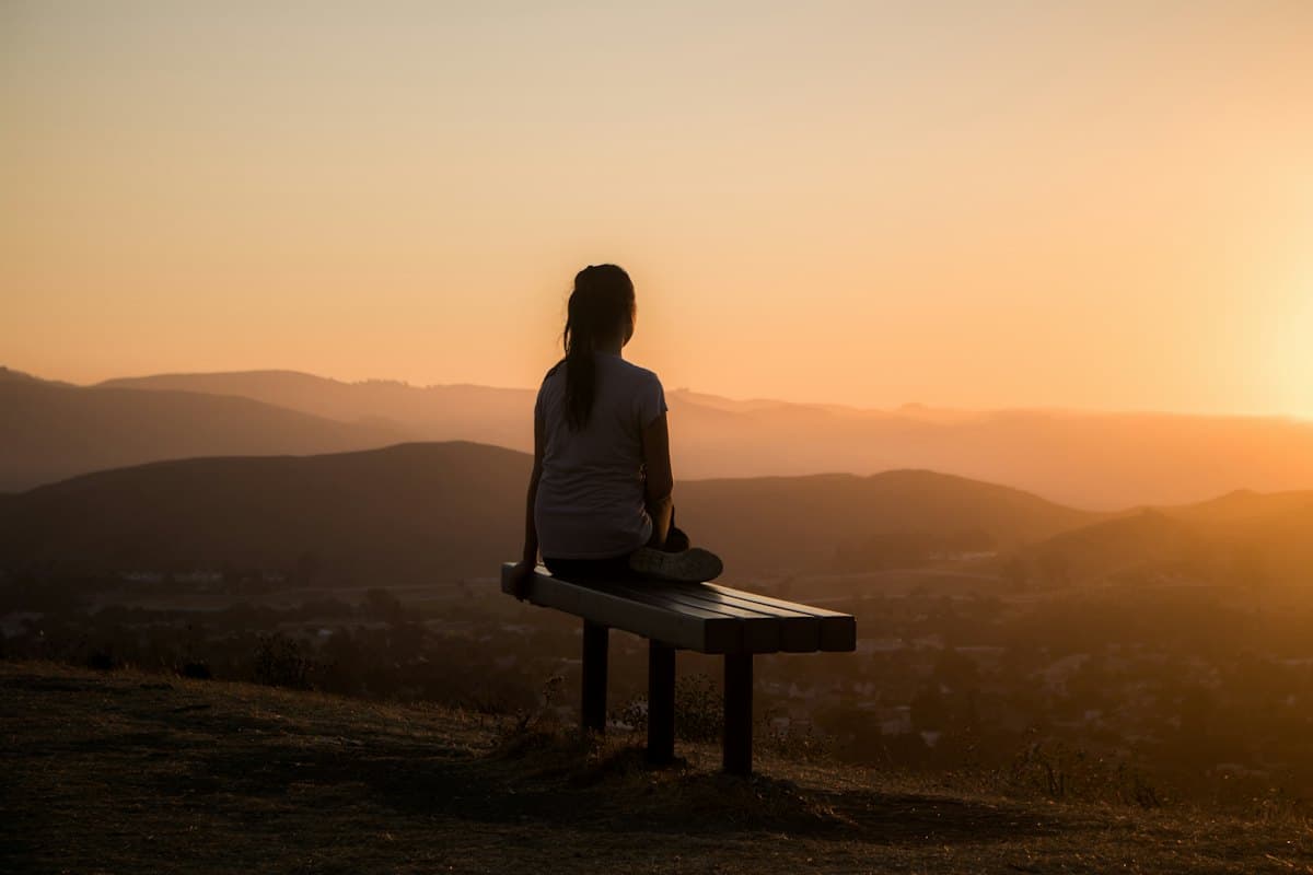 Person sitting on a bench looking out at mountains